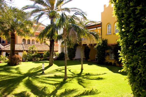 圣玛丽亚港Apartamentos Soho Boutique Vistahermosa的一座楼前有棕榈树的院子