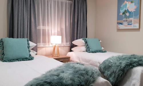 罗托鲁瓦Rose Apartments Unit 3 Central Rotorua - Accommodation & Spa的客房设有两张带绿色靠垫的床。