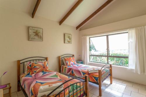 拉罗汤加Mango Cottage的带窗户的客房内的两张床
