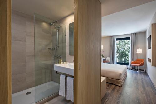 里斯本EXE自由酒店的一间带水槽和淋浴的浴室以及一张床