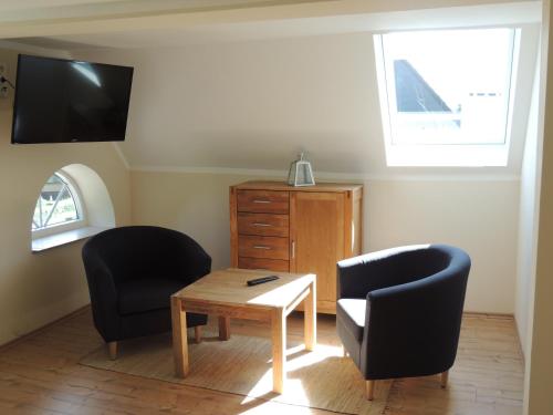 格洛米茨Lindenhof的客厅配有两把椅子和一张桌子