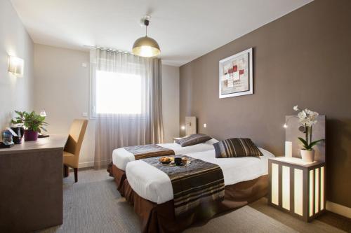 马赛Appart'City Confort Marseille Centre Prado Vélodrome的酒店客房配有两张床和一张书桌