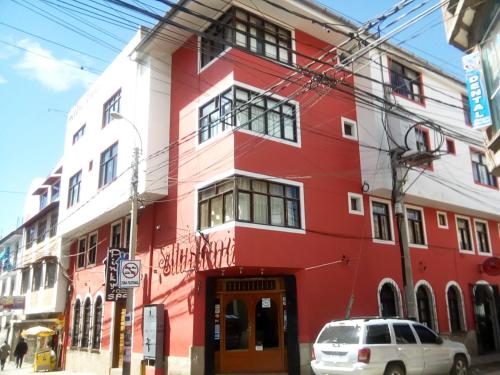 普诺Hostel Sillustani Inn Puno的街道拐角处的红白色建筑