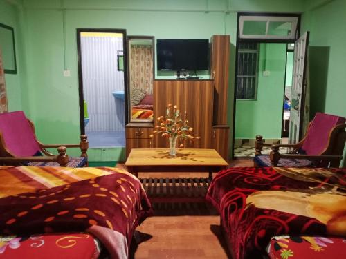 大吉岭Zimba Happy Home Stay的客房设有两张床、一张桌子和一台电视机。