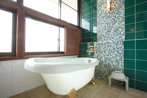 松岛町Hotel Ubudo的浴室设有白色浴缸和绿色瓷砖。