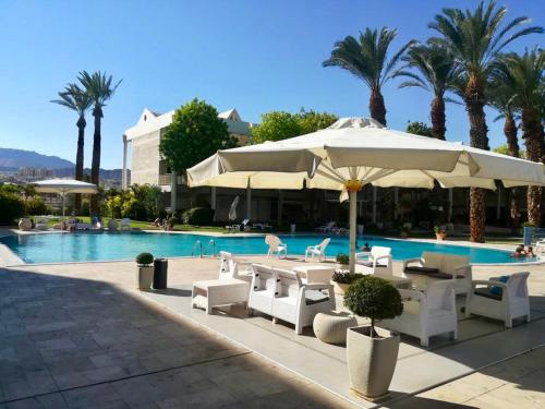 埃拉特Esterin Royal Park Apartments Eilat的一个带桌椅和遮阳伞的游泳池