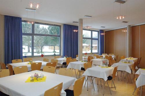 什未林A&S Ferienzentrum Schwerin的餐厅设有白色的桌椅和窗户。