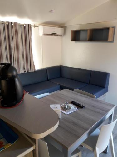 勒米伊Mobil home florida - camping les cigales - 4 étoiles的客厅配有蓝色的沙发和桌子