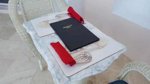 拿骚西大洋精品酒店的一张桌子,椅子上摆放着一本书和红色的餐巾
