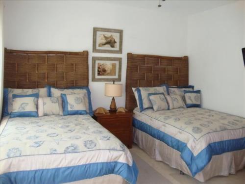 蓬塔卡纳Cap Cana Luxurious Marina Condo的卧室设有两张蓝色和白色的床