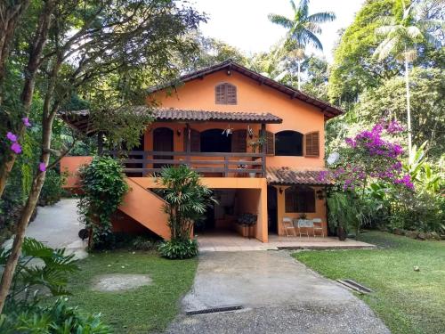 佩尼多Casa em penedo com cachoeira的一座种植了树木的橙色房子,设有阳台