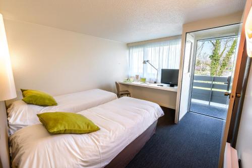 图卢兹瑟斯库艾钟楼酒店的酒店客房设有两张床、一张书桌和一个窗户。