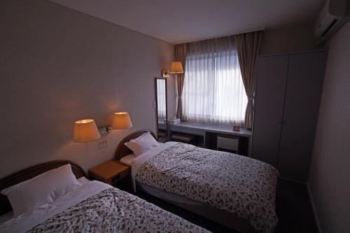 八幡平市Pension Entre - deux - Mers的酒店客房设有两张床和窗户。