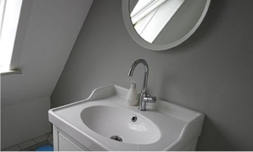 霍瓦赫特Ferienwohnung am Strandweg的白色的浴室设有水槽和镜子