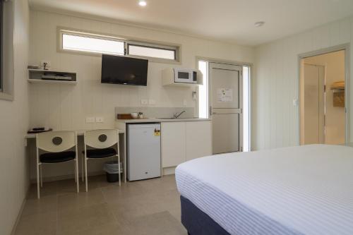 EromangaCooper's Country Lodge的一间带一张床和一张书桌的卧室和一间厨房