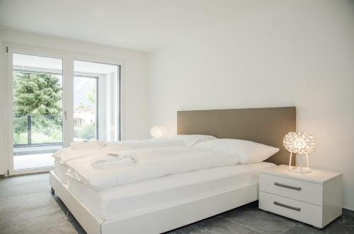 因特拉肯Apartment JungfrauCenter Bällenhöchst - GriwaRent AG的白色的卧室设有白色的床和窗户。