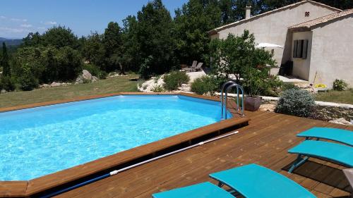 Saint-Privat-de-ChampclosLou Mazet的木制甲板上带蓝色椅子的游泳池