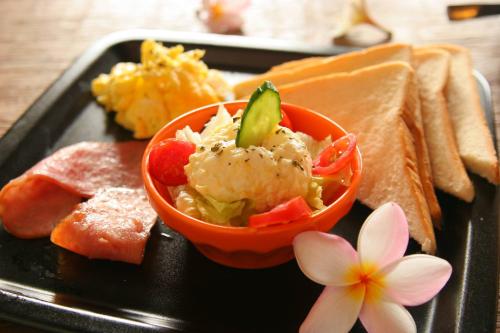 满洲乡垦丁阿飞冲浪旅店佳乐水NANU馆 的一块黑色的盘子,上面有一碗食物和一朵花