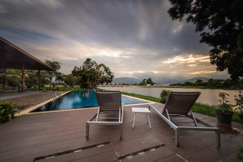 宗通Doi Inthanon Riverside resort的游泳池旁的甲板上摆放着两把椅子