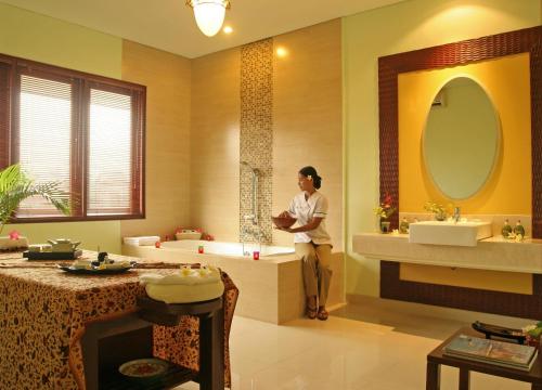 库塔拉尼酒店及水疗中心的站在带两个水槽和浴缸的浴室中的女人