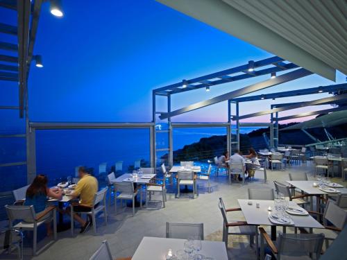 帕诺尔莫斯斯科派洛斯阿德里纳度假酒店和Spa中心的坐在餐厅屋顶桌子上的人