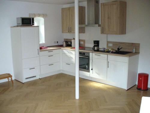 吕讷堡Ferienwohnung Riedner的厨房铺有木地板,配有白色橱柜。