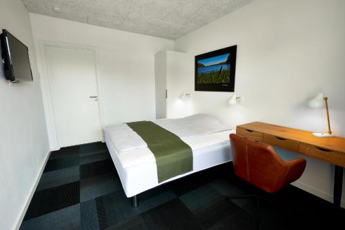 霍尔斯特布罗Hotel Phønix的一间卧室配有一张床、一张书桌和一台电视。