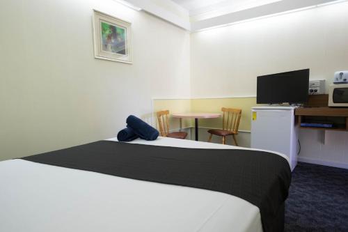 天鹅山先锋站汽车旅馆的一间卧室配有一张床和一张桌子及一台电视