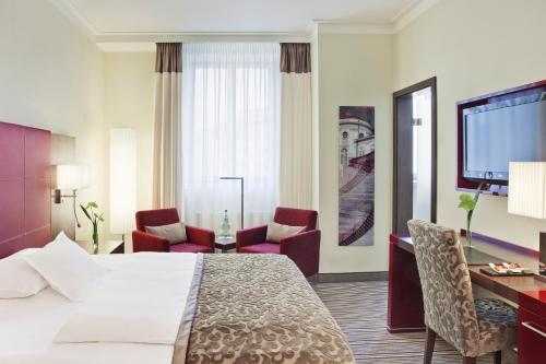 斯图加特施泰根博阁格拉夫齐柏林酒店的酒店客房,配有一张床、一张桌子和椅子