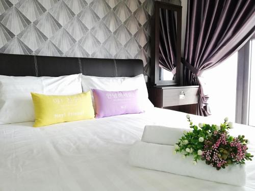 新山Country Garden Danga Bay , Royal Strand的卧室配有白色的床和2个色彩缤纷的枕头