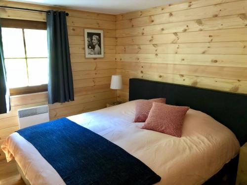 比林根Chalet de charme, le "Caribou Lodge", Eifel belge的卧室配有一张床铺,位于带木墙的房间内