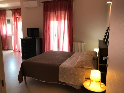 奥斯图尼Apartment Antonella的一间卧室配有床、电视和红色窗帘