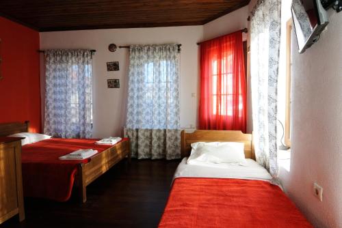 Psarádes腓力酒店 的宿舍间的两张床,设有红色的墙壁和窗户
