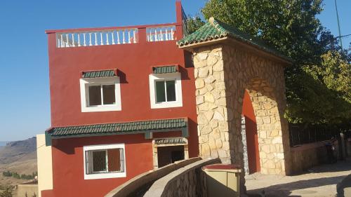 Aïn LeuhHotel Ain Leuh的一座红色的建筑,有拱门和塔