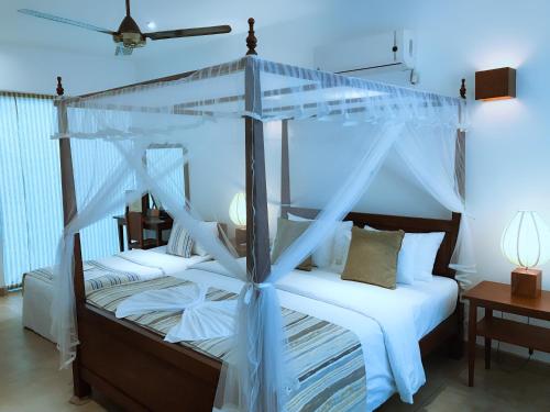 拉维尼亚山科扎锡兰酒店的卧室配有带白色床单的天蓬床