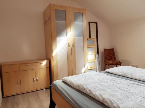SpirkelbachHöllenbergblick的一间卧室配有一张床、一个橱柜和一把椅子