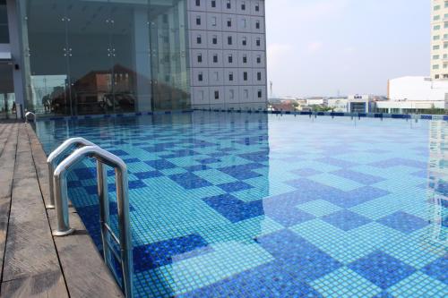 梭罗HARRIS Hotel & Conventions Solo的一座建筑物边的蓝色瓷砖游泳池