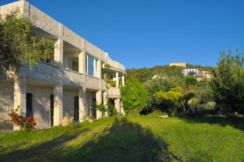 派莱卡斯Lemoni Apartments的一座石头房子,位于一座小山上,拥有一座绿色的庭院