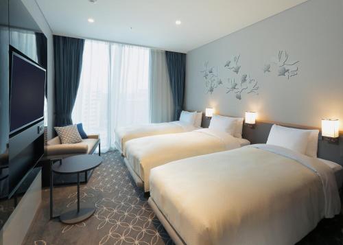 首尔首尔格拉斯丽酒店的一间酒店客房,设有三张床和一台平面电视