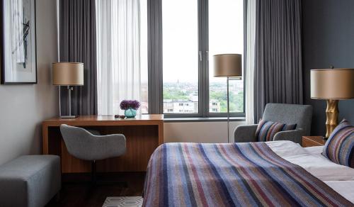 科隆AMERON Köln Hotel Regent的酒店客房设有一张床、一张书桌和窗户。