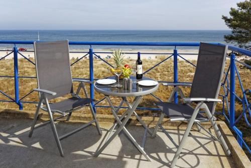 特拉森海德Haus auf der Duene Fewo Ostseeblick的海滩阳台的一张桌子和两把椅子