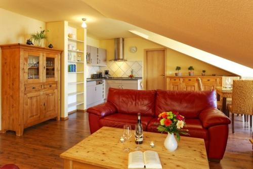 特拉森海德Haus auf der Duene Fewo Ostseeblick的客厅配有红色皮革沙发和桌子
