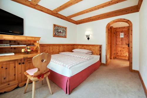 圣莫里茨水晶酒店的一间卧室配有一张床、一张书桌和一台电视