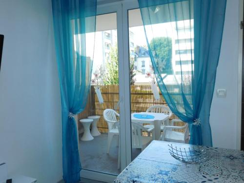 卢尔德Le petit nid的客房设有带蓝色窗帘的阳台、桌子和椅子
