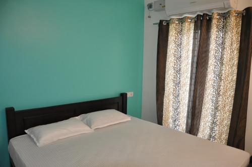 蒂鲁奇奇拉帕利Moonlight Residency的一张位于带蓝色墙壁和窗帘的房间的床铺