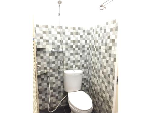 日惹Rumah Baraka的浴室设有卫生间和铺有格子瓷砖的淋浴。