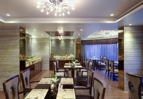 孟买Hotel Suba Galaxy Mumbai的一间带桌椅和吊灯的餐厅