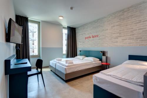 米兰米兰兰布雷特美宁厄尔酒店的一间卧室配有两张床、一张桌子和一台电视。