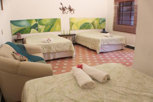 库埃纳瓦卡Casa Madero Rooms的客房设有两张床和一张带毛巾的沙发。