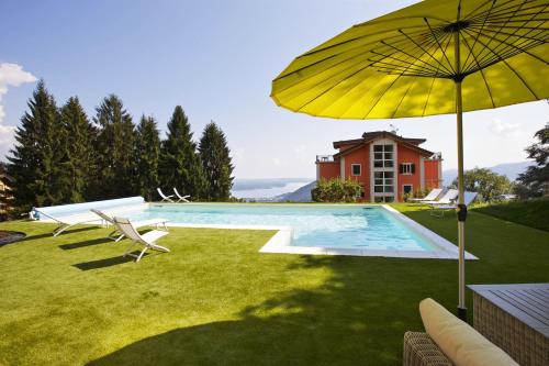 MiazzinaResidence alle Ville的一座带黄色遮阳伞和椅子的游泳池以及一座房子